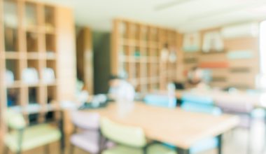 School classroom in blur background without young student; Blurry view of elementary class room no kid or teacher with chairs and tables in campus. Vintage effect style pictures.